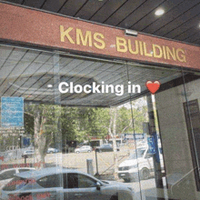 a car is parked in front of a kms building that is closed .