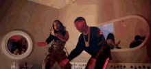 a man and woman are dancing in front of a mirror in a room .