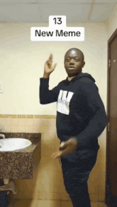 a man in a black hoodie is dancing in front of a sink with the number 13 on it