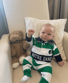 a baby wearing a green and white notre dame outfit