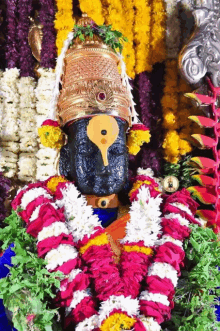 a statue of a deity is surrounded by garlands of flowers and leaves