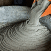 a close up of a person pouring concrete into a bowl .