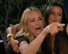 two women are sitting next to each other and one of them is pointing at something .