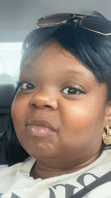 a close up of a woman 's face with sunglasses and earrings