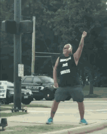 a man wearing a shirt that says " dancing for smiles " is standing in front of a police car