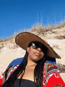 a woman wearing a straw hat and sunglasses is laying on a beach