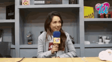 a woman sitting at a table with a microphone in front of a shelf with a sign that says ' radio zoo '