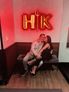 a man and a woman are kissing in front of a hk sign