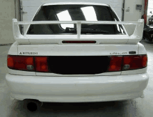 the rear end of a white mitsubishi lancer with a spoiler on top of it .