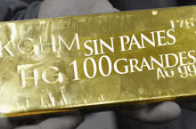 a person is holding a gold bar that says kghm sin panes hg 100 grandes au 99