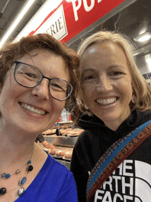 two women are posing for a picture and one is wearing a north face sweatshirt