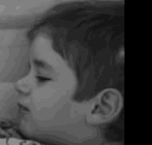 a black and white photo of a young boy 's face and ear .