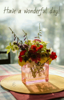 a vase of flowers sits on a table with the words have a wonderful day