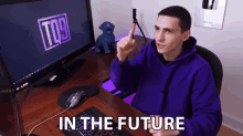 a man in a purple hoodie is sitting in front of a computer with the words in the future on the screen