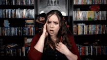 a woman holds her head in front of a shelf full of dvds including one that says ' potato chips ' on it