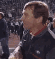 a man is holding a bag of popcorn in front of a crowd of people at a football game .