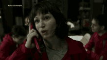 a woman in a red jacket is talking on a cell phone in a dark room .