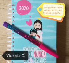 a victoria c. pen sits next to a spiral notebook