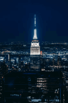 the empire state building is lit up at night with a city in the background