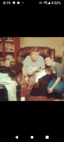 a man is kneeling next to an elderly woman sitting in a chair in a living room .