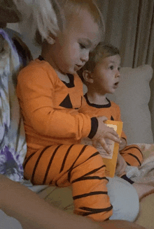 two young boys wearing halloween pajamas are sitting on a couch