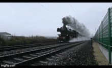 a train is going down the tracks with smoke coming out of the engine
