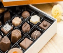 a box filled with chocolates is sitting on a wooden table .