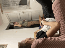 a man is laying on a couch while another man sits on the floor