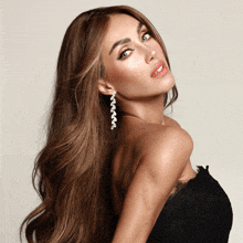 a woman wearing a black strapless dress and earrings looks to the side