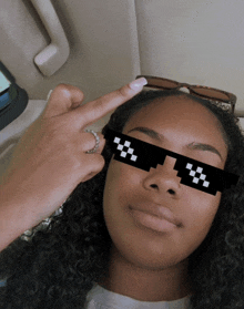 a woman wearing pixelated sunglasses with the letter t on it