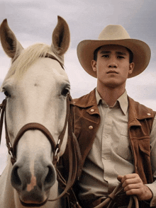 a man in a cowboy hat is riding a white horse