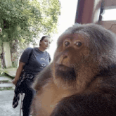 a woman standing next to a monkey wearing a shirt that says ' lc2 ' on it