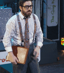 a man in a striped shirt and suspenders holds a briefcase in front of a sign that says the great wall