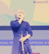 a woman playing a violin in front of a screen that says official