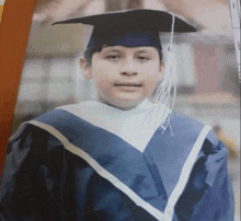 a young boy wearing a graduation cap and gown poses for a picture