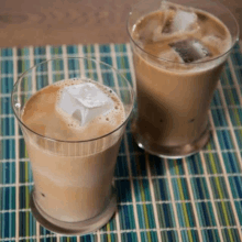 two glasses of iced coffee with ice cubes on a table