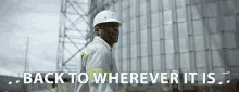 a man wearing a hard hat stands in front of a building with the words back to wherever it is