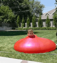 a little boy is playing with a large red balloon