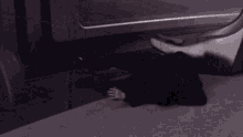 a person is laying on the ground under a car in the dark .