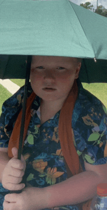 a boy in a hawaiian shirt is holding an umbrella