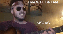 a man wearing sunglasses and a bandana playing a guitar with the words live well be free $ isaac above him