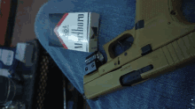 a box of marlboro cigarettes is next to a gun