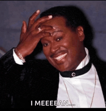 a man in a tuxedo is smiling and holding his hand to his forehead with the words i meeeean below him