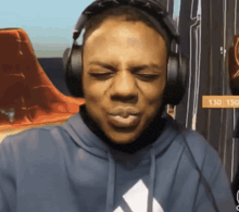 a man wearing headphones is making a funny face in front of a sign reading 130 150