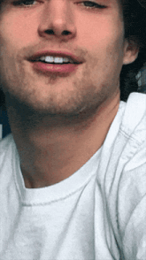 a close up of a man 's face with a white t-shirt on