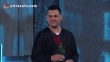 a man is holding a red rose in front of a eltrecetv.com logo