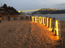 the word tequila is lit up on the beach