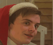 a young man wearing a santa hat is smiling for the camera