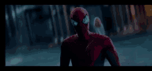 a man in a spiderman costume is standing in a dark street .