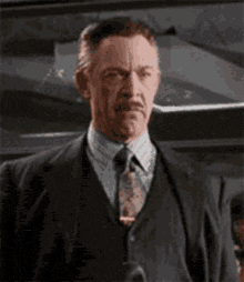 a man in a suit and tie is standing in a dark room .